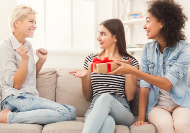 Two girls surprising their friend with a tech gift