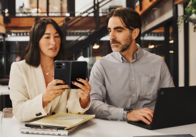 Two people looking at a black Google Pixel 9.